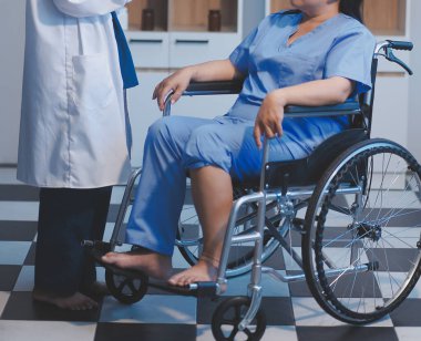 Asyalı, genç, profesyonel, dost canlısı mavi hastane üniformalı kadın hemşire yaşlı, yaşlı, sağlıksız, dört bacaklı, yürüyen bir hastanın fiziksel terapisine yardım ediyor..