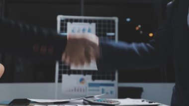 Modern ofiste iş ekibi el sıkışıyor.