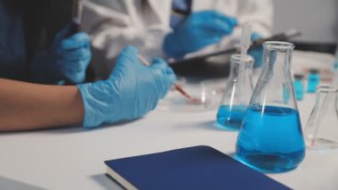 Laboratuvar önlüklü bilim adamı laboratuarda sıvı tüpü tutuyor.