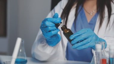 Laboratuvarda sıvı içeren tüp ve test tüpü tutan bilim adamı, kapatın.