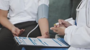 Steteskoplu genç Asyalı doktor ve hastanede oturan hasta.