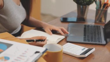 Evde dizüstü bilgisayar ve tabletle çalışan genç bir kadın..