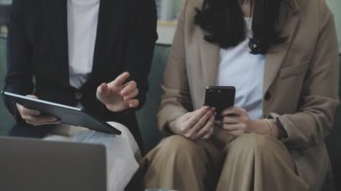 İki genç iş kadını ofiste tablet bilgisayar kullanıyor.