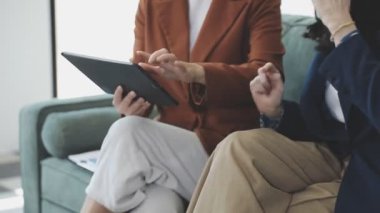 İş kadını ofiste koltukta otururken tablet kullanıyor.