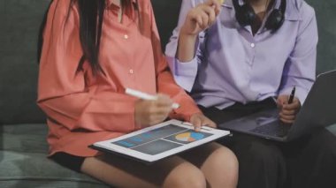 Genç Asyalı kadınlar kanepede otururken dijital tablet kullanıyorlar..