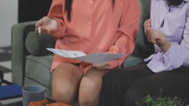 Kanepede otururken dijital tablet kullanan genç bir kadın.