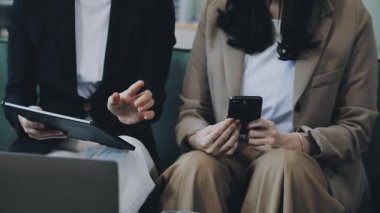 İki iş kadını bir kafede otururken dizüstü bilgisayar kullanıyor..