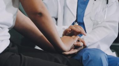 Doktor klinikte hastanın elini tutuyor.