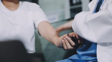 Doktor hastanın elini tutuyor.