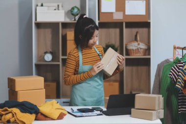 Vlogger, blog yazarı, küçük KOBİ iş kadını güzel bir kadın cep telefonuyla kıyafetleri satıyor canlı yayın satışı yapıyor, ana ofiste ürün sunumu detaylarını gösteriyor, girişimci ekommerce