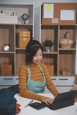 Vlogger, blog yazarı, küçük KOBİ iş kadını güzel bir kadın cep telefonuyla kıyafetleri satıyor canlı yayın satışı yapıyor, ana ofiste ürün sunumu detaylarını gösteriyor, girişimci ekommerce