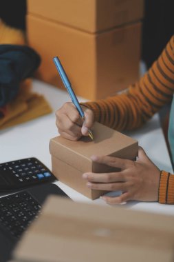 Vlogger, blog yazarı, küçük KOBİ iş kadını güzel bir kadın cep telefonuyla kıyafetleri satıyor canlı yayın satışı yapıyor, ana ofiste ürün sunumu detaylarını gösteriyor, girişimci ekommerce