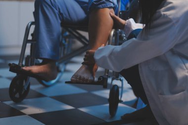 Asyalı, genç, profesyonel, dost canlısı mavi hastane üniformalı kadın hemşire yaşlı, yaşlı, sağlıksız, dört bacaklı, yürüyen bir hastanın fiziksel terapisine yardım ediyor..