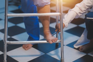 Asyalı, genç, profesyonel, dost canlısı mavi hastane üniformalı kadın hemşire yaşlı, yaşlı, sağlıksız, dört bacaklı, yürüyen bir hastanın fiziksel terapisine yardım ediyor..