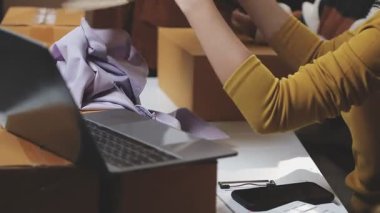 Kadın dizüstü bilgisayar kullanıyor ve kutuları paketliyor