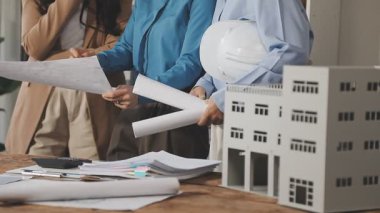 Genç mühendis ve bayan mimar planlar üzerinde çalışıyor ve iş yerindeki planları tartışıyorlar..