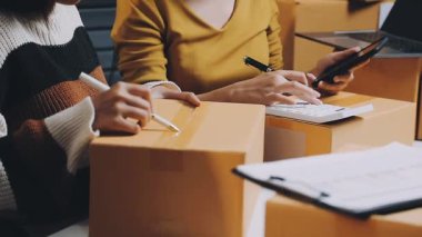 Dizüstü bilgisayarı ve arka planda kutusu olan takım elbiseli genç bir kadın..