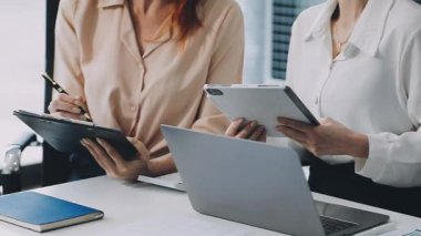 İki genç iş kadını masada oturuyorlar ve ellerinde tablet var.