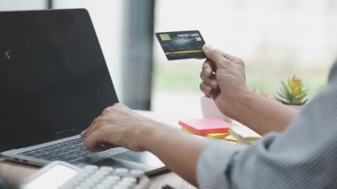 Genç Asyalı bir kadın online kredi kartı, internet alışveriş konsepti, online alışveriş için laptop ve kredi kartı kullanıyor..