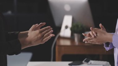 Genç işadamı ofiste iş arkadaşıyla tokalaşıyor.