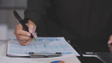 İşadamı, elinde kalemle ofiste yazı yazıyor.