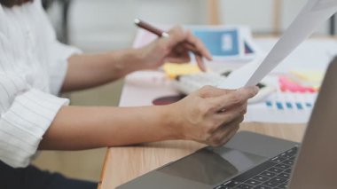 Ofiste belgelerle ve bilgisayarla çalışan bir iş kadını..