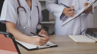 Tıp üniformalı kadın doktor notlar yazıyor.