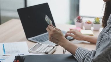 Kredi kartı tutan ve online ödeme için dizüstü bilgisayar kullanan iş kadını, İnternet alışveriş kavramı