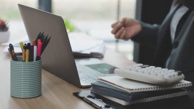 İş kadını el bilgisayarı kullanıyor. Masasında boş bir defter var.