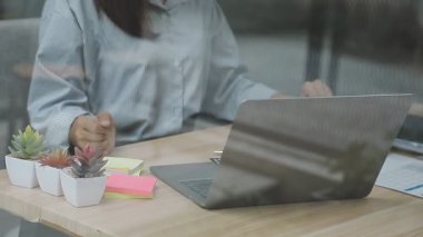 Genç bir iş kadını dizüstü bilgisayarla çalışıyor ve modern merkez ofisteki masada kredi kartı tutuyor..