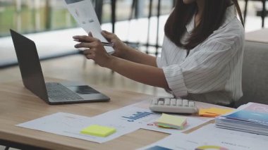 İş kadını ofis masasında dizüstü bilgisayar ve mali belge kullanıyor..