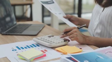 Genç Asyalı iş kadını ofisteki mali tabloları analiz ediyor.