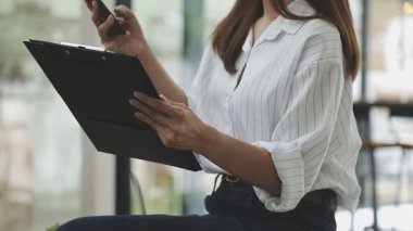 Genç Asyalı iş kadını modern ofiste dijital tablet kullanıyor.