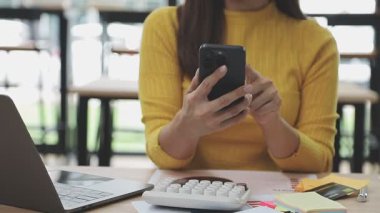 Akıllı telefon ve dizüstü bilgisayar kullanan genç bir kadın.