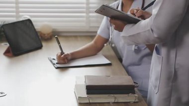 Beyaz önlüklü genç doktor notlar yazıyor.