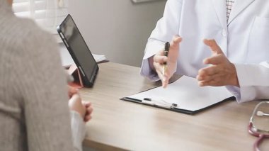 Hastanedeki hastasına danışmanlık yaparken elinde kalem tutan erkek doktor.