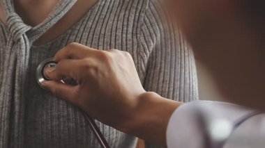 Klinikte steteskopu inceleyen bir doktor. Kadın hastayı muayene ediyor..