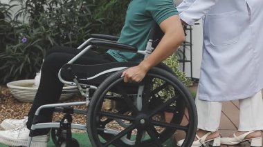 Tekerlekli sandalyede kocasıyla yürüyen engelli bir kadın..