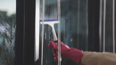 Siyah takım elbiseli bir kadının eli camları yıkıyor.