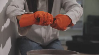 Genç bir adam silindirle bir duvar boyuyor..