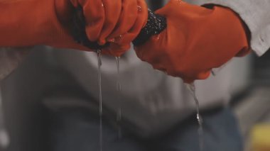 Eldiven ve eldiven giyen bir işçi atölyede silahla çalışıyor.