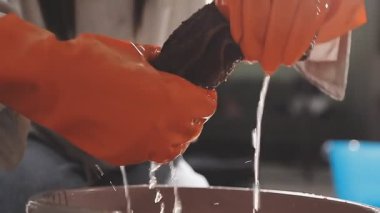 Siyah önlüklü işçi boya için fırçalı bir tabak yapar.