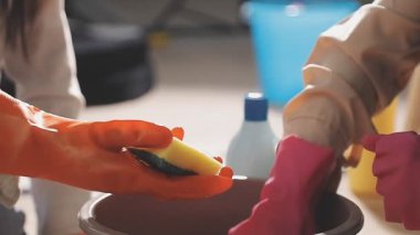 Siyah gömlekli ve kırmızı eldivenli bir adam eski bir işçinin elinde bir şişe sıvı tutuyor.