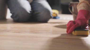Eldivenli bir kadın bez parçasıyla masasını temizliyor.