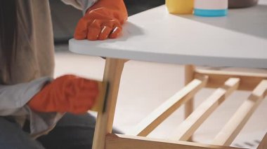 Genç bir kadın, tahta bir sandalyeyi fırçayla boyuyor.