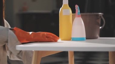 Kadın mutfak masasını bez parçasıyla temizliyor.