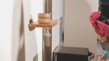 Eldivenli bir kadın mutfakta deterjanla ellerini yıkıyor.