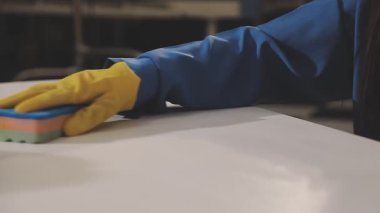 Mutfakta fırçası olan mavi eldivenli ve beyaz gömlekli bir kadın.