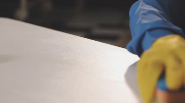 Beyaz eldivenli bir adam elinde bir boya parçası tutuyor..