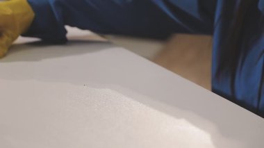 Mavi eldivenli bir adam evde bez ve bezle masayı temizliyor. Temizlik ve temizlik kavramı